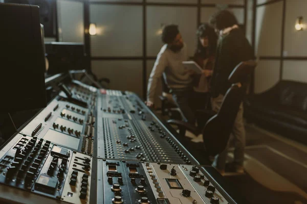 Blurred group of musicians spending time at recording studio with graphic equalizer — Stock Photo