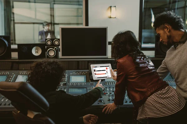 Productores de sonido usando tableta juntos en el estudio de grabación con el sitio web soundcloud en pantalla - foto de stock