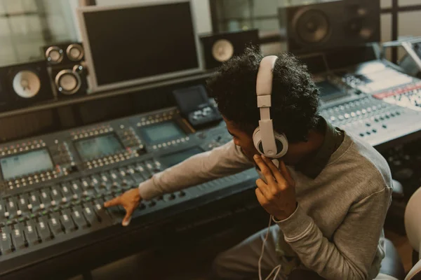 Молодой африканский американский звукорежиссер работает с аналоговым эквалайзером в студии — стоковое фото