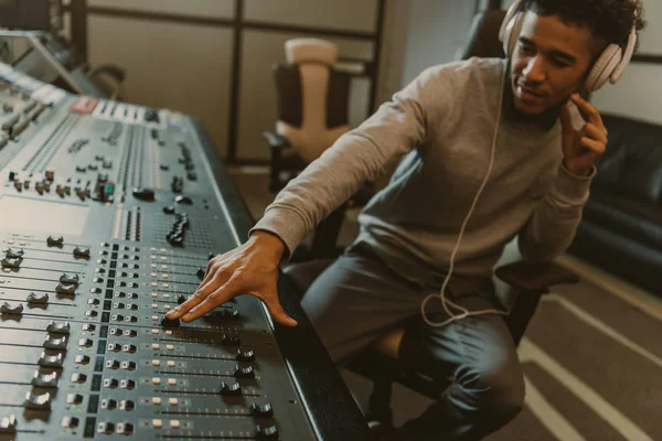 Joven productor de sonido guapo trabajando con ecualizador analógico en el estudio - foto de stock