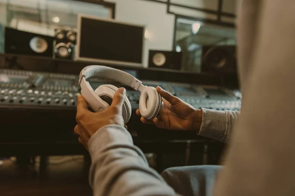 Tiro recortado de produtor de som com fones de ouvido sentado em estúdio — Fotografia de Stock