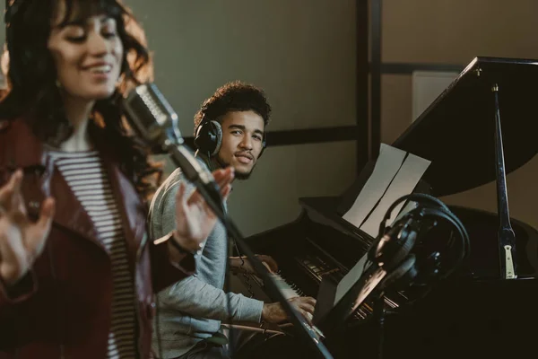 Young handsome piano player looking at singer performing song — Stock Photo