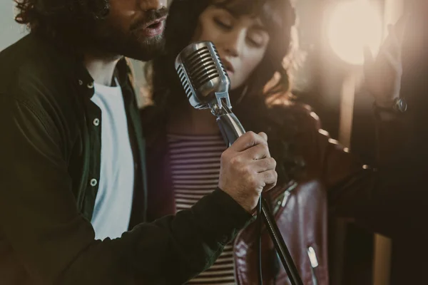 Plan rapproché de jeune couple chantant avec microphone vintage — Photo de stock