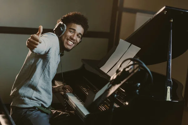 Feliz joven pianista mostrando el pulgar hacia arriba - foto de stock