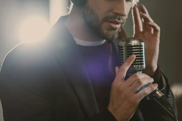 Atractiva cantante joven en auriculares cantando canción en el estudio - foto de stock