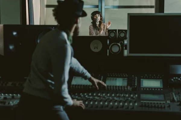 Sound producer in hat recording song at dark studio — Stock Photo