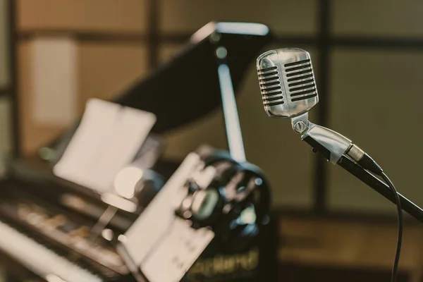 Close-up shot of vintage microphone in front of blurred piano — Stock Photo