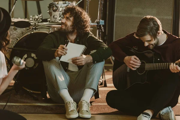 Junge Musikband sitzt mit Notizblöcken auf dem Boden und redet — Stockfoto