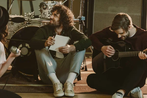 Young music band sitting on floor with notepads and talking — Stock Photo