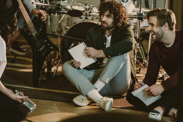 Banda de música sentada en el suelo con bloc de notas y hablando - foto de stock