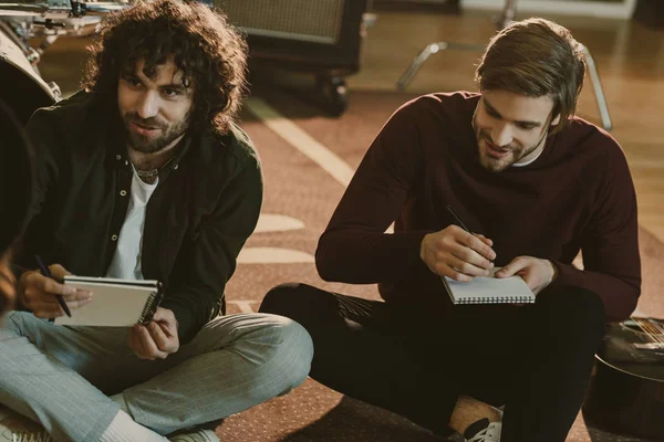 Young music band colleagues writing lyrics together while sitting on floor — Stock Photo