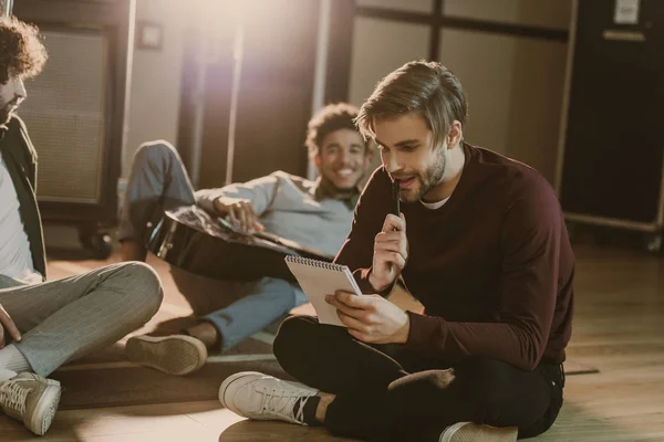 Music band writing lyrics together while sitting on floor — Stock Photo