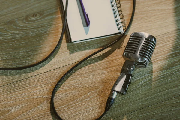 Vista superior do microfone vintage com fio deitado na mesa de madeira com notebook em branco — Fotografia de Stock