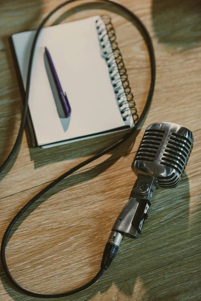 Vista superior do microfone retro com fio deitado na mesa de madeira com notebook em branco — Fotografia de Stock