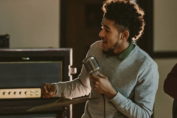 Guapo cantante afroamericano realizando canción con micrófono - foto de stock