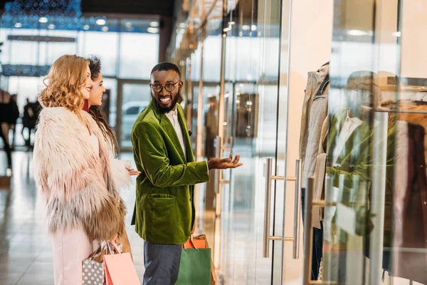 Вид збоку усміхнених стильних багатоетнічних людей купують разом у торговому центрі — стокове фото