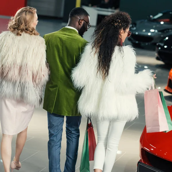 Stylish young shoppers walking by auto showroom — Stock Photo