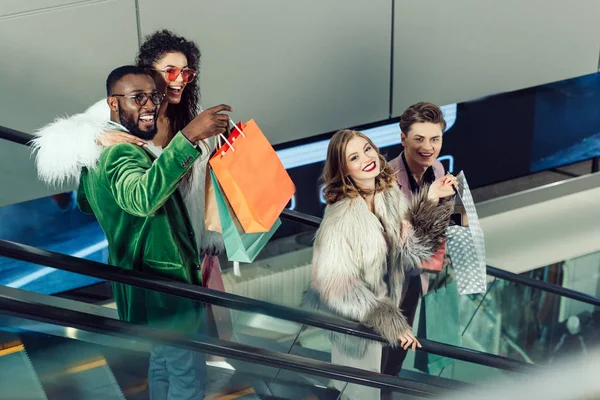 Young stylish group of shoppers on escalator at shopping mall — Stock Photo