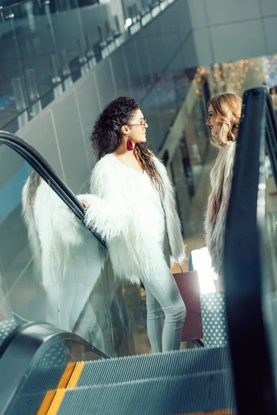 Junge Frauen reden auf Rolltreppe in Einkaufszentrum — Stockfoto