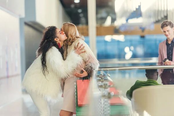 Вид сбоку стильных женщин, приветствующих друг друга в торговом центре — стоковое фото