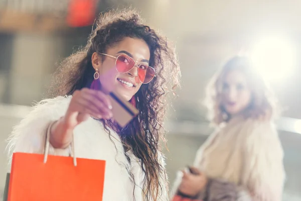 Mujer joven y elegante en abrigo de piel con tarjeta de crédito de oro en las compras - foto de stock