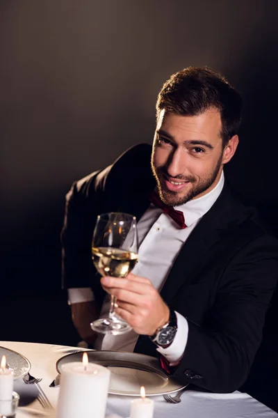 Hombre barbudo sonriente con copa de vino sentado en el restaurante - foto de stock