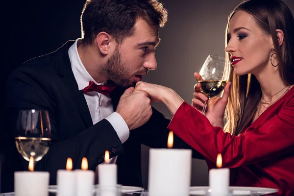 Donna che beve vino mentre l'uomo le bacia la mano su appuntamento romantico nel ristorante — Foto stock