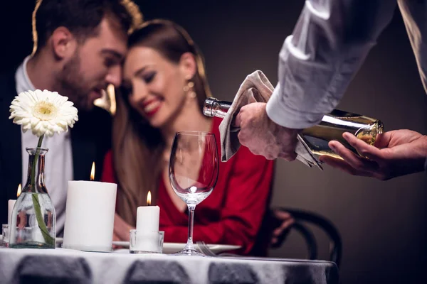 Camarero vertiendo vino mientras hermosa pareja teniendo una cita romántica en el restaurante el día de San Valentín - foto de stock