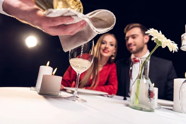 Selective focus of waiter pouring wine while couple having romantic date in restaurant — Stock Photo