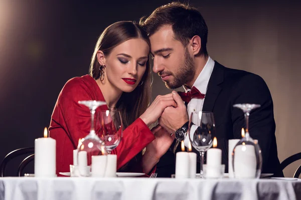 Beautiful tender couple holding hands in restaurant — Stock Photo