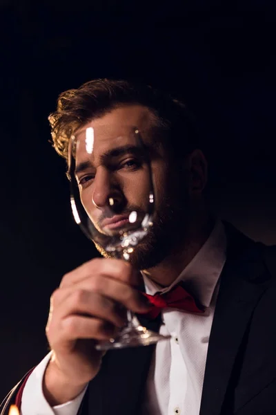Bel homme barbu regardant à travers le verre de vin — Photo de stock