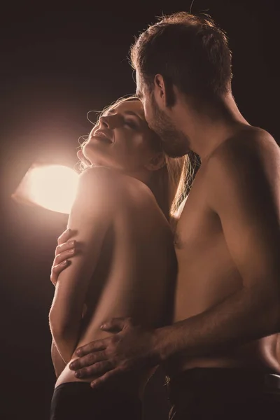 Amantes nus felizes abraçando, em marrom com luz de volta — Fotografia de Stock