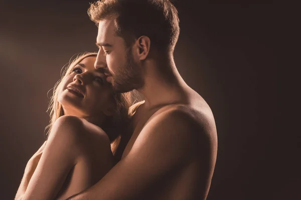 Glückliche nackte Liebende, die sich umarmen und einander anschauen, auf braun — Stockfoto