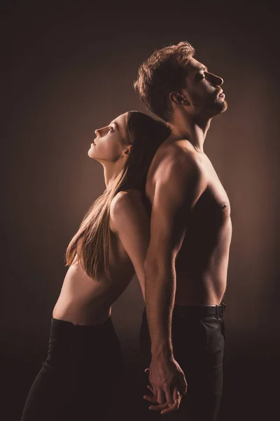 Amoureux debout dos à dos et tenant la main, isolés sur brun — Photo de stock