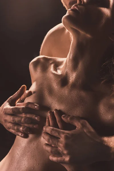 Обрізаний вид на хлопця, який торкається грудей своєї оголеної подруги, на коричневому — стокове фото