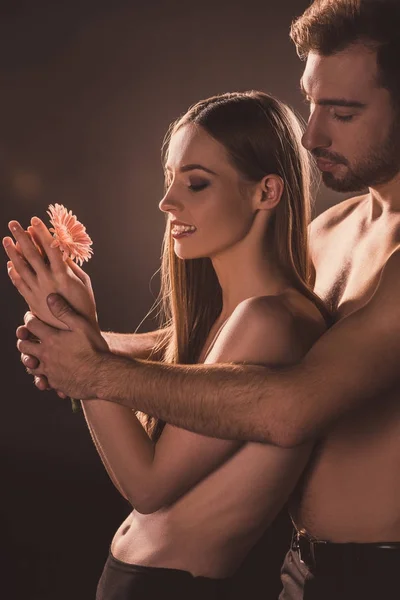 Amantes nus abraçando e segurando flor, em marrom — Fotografia de Stock