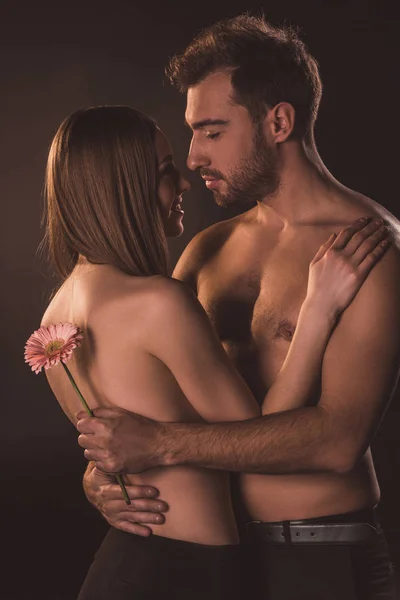 Tendre couple étreignant et tenant fleur, isolé sur brun — Photo de stock