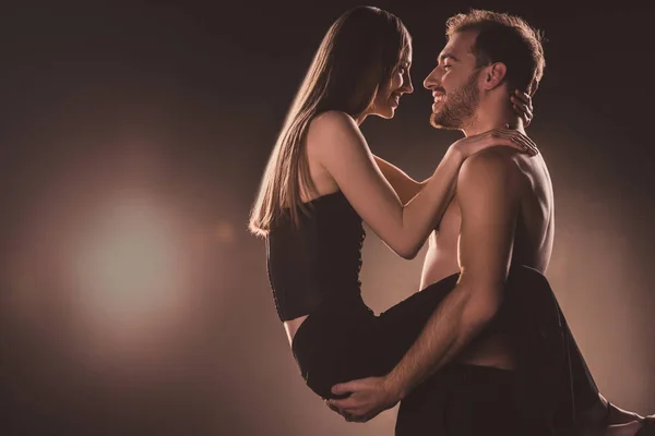 Couple romantique étreignant et se regardant, sur brun avec contre-jour — Photo de stock