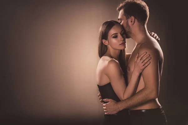 Sensual nude lovers embracing, on brown with copy space — Stock Photo