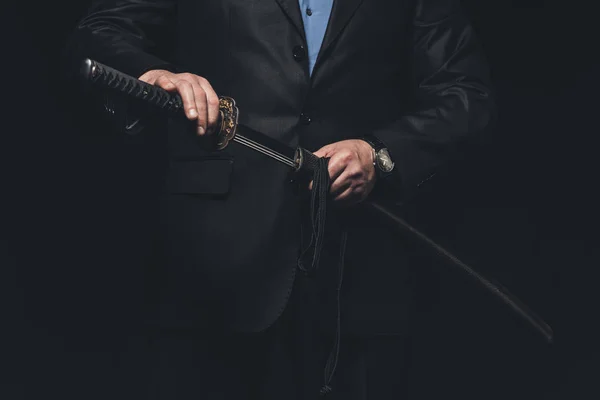 Recortado disparo de hombre en traje sacando su espada katana aislado en negro — Stock Photo