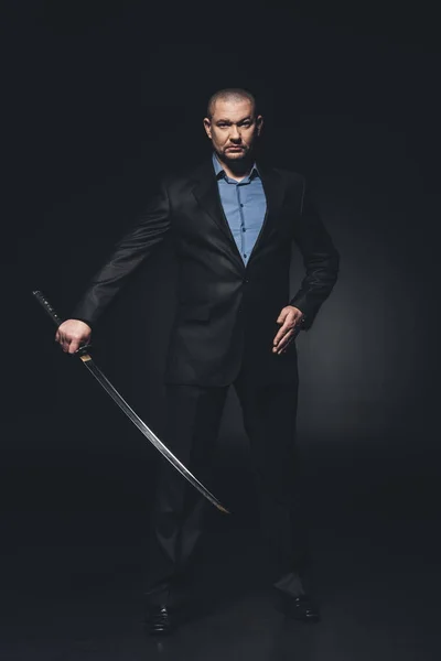 Modern samurai in formal suit with katana sword on black — Stock Photo