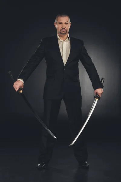 Hombre disfrazado con espadas duales katana sobre negro - foto de stock