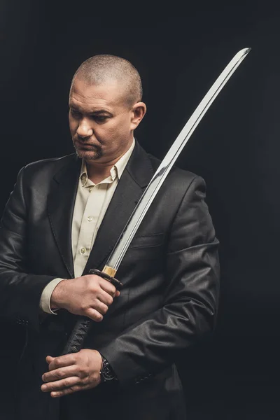 Homme en costume avec épée katana isolé sur noir — Photo de stock