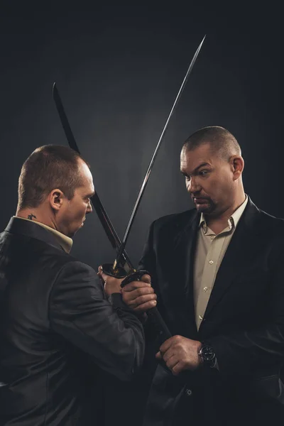 Geschäftsleute kämpfen mit Katana-Schwertern auf Schwarz — Stockfoto