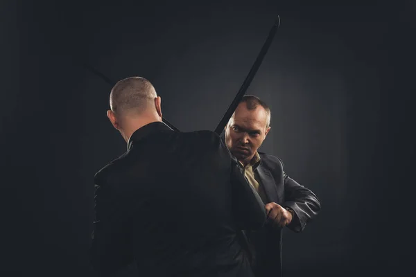Geschäftsleute kämpfen mit Katana-Schwertern auf Schwarz — Stockfoto