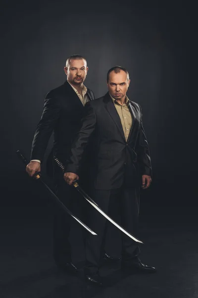 Businessmen with katana swords isolated on black — Stock Photo