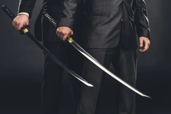 Cropped shot of modern samurai with katana swords isolated on black — Stock Photo