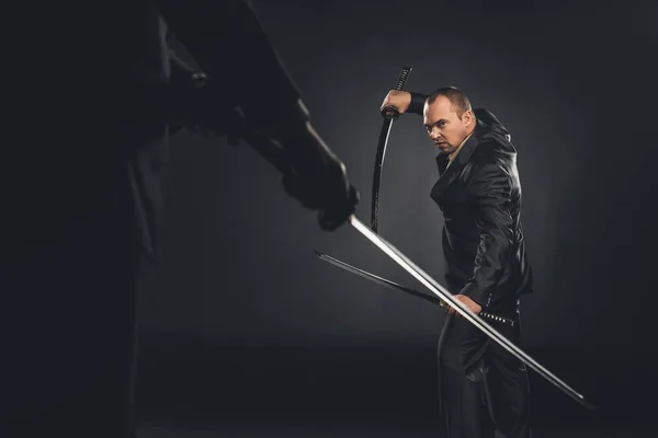 Mature modern samurai in suit ready to fight on black — Stock Photo