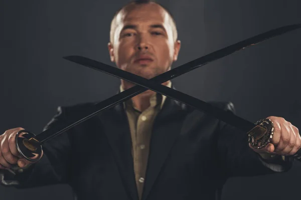 Close-up shot of man in suit with katana sword on black — Stock Photo