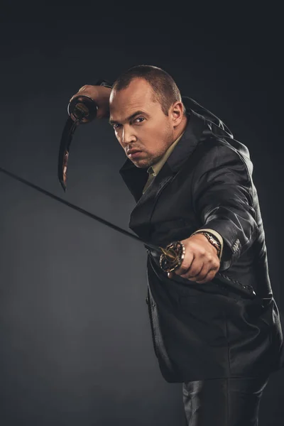 Man in defence pose in suit with katana swords on black — Stock Photo